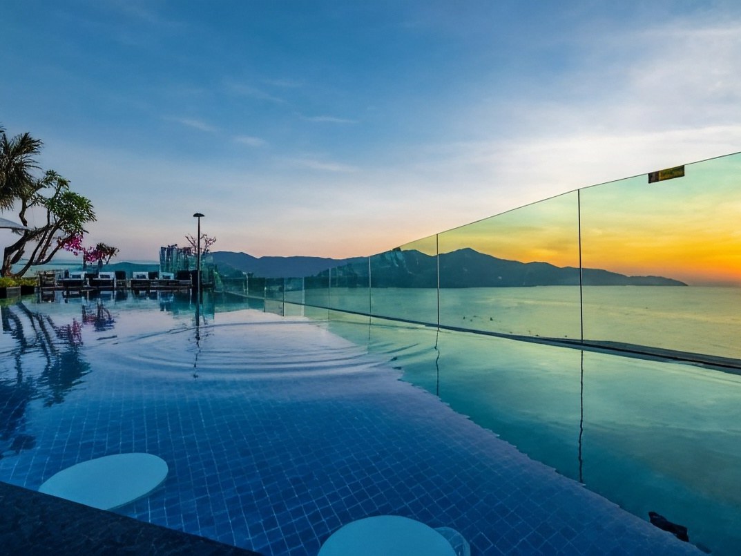 Infinity pool edge at sunset with the sea and a headland across the water