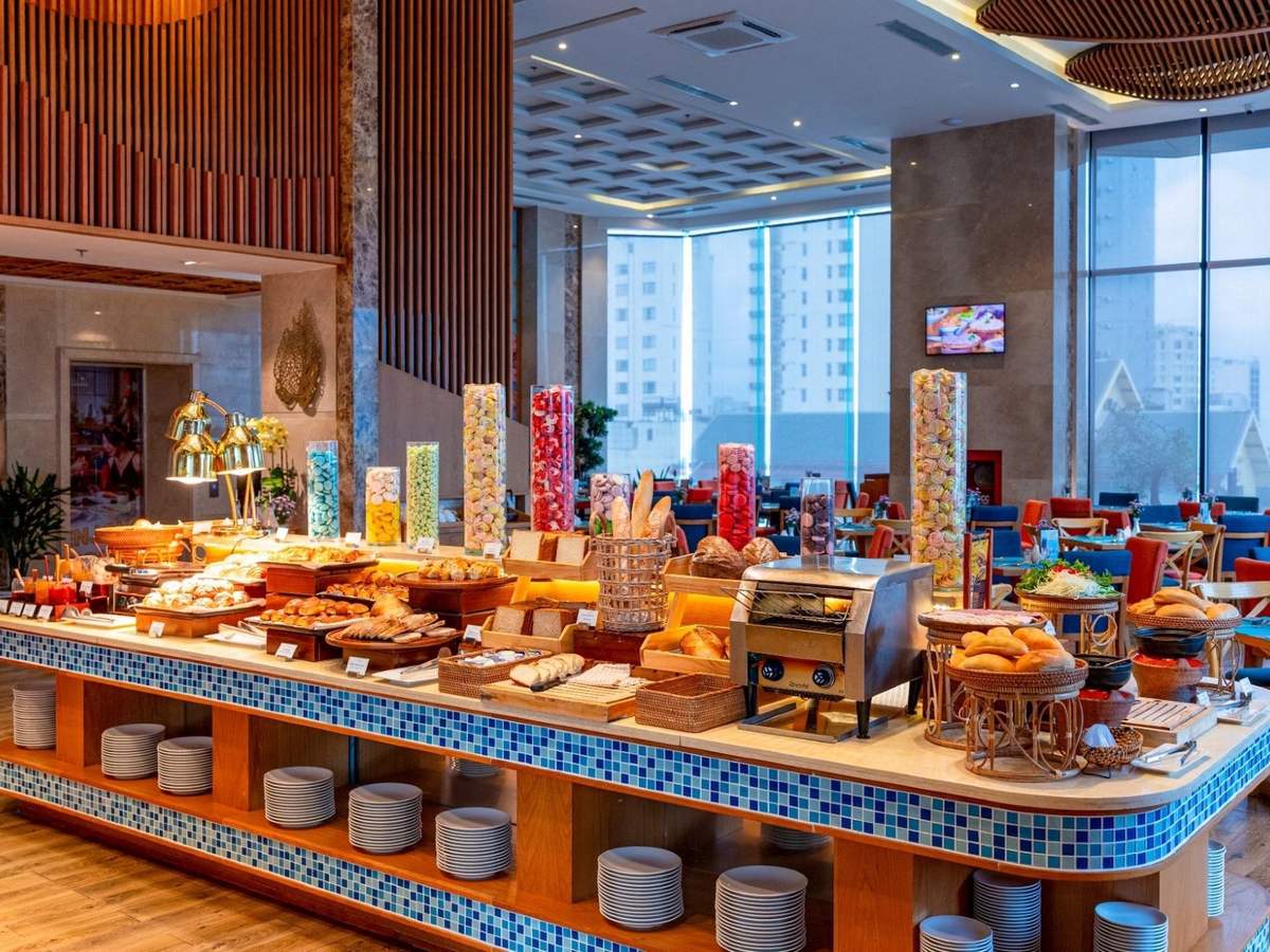 Long breakfast buffet with tiled counters, glass jars and hot dishes in a bright restaurant