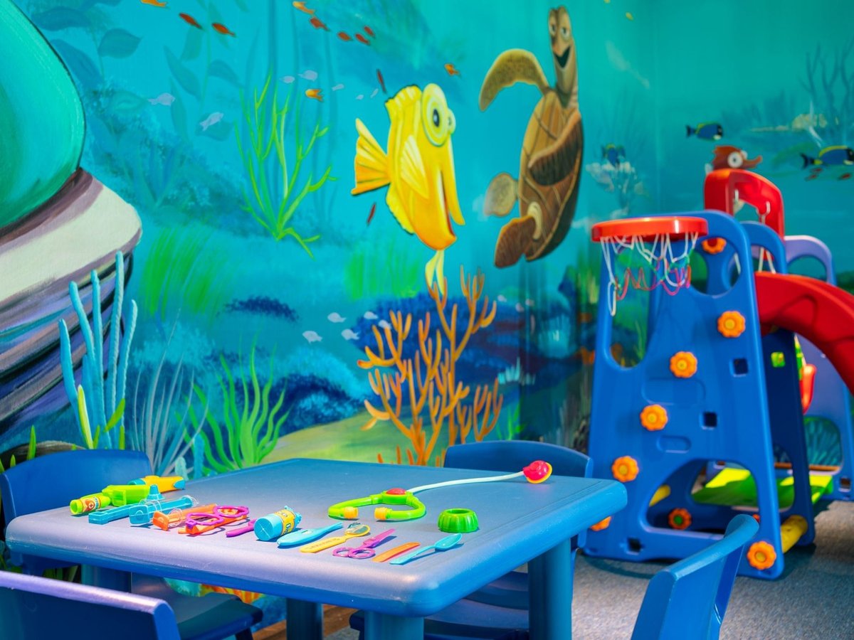 Children’s playroom with a sea-life mural, a small slide and a low craft table