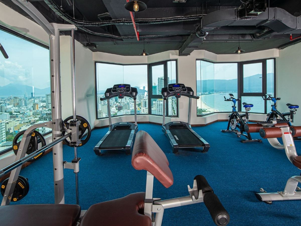Small gym with treadmills and exercise bikes by tall windows over the city