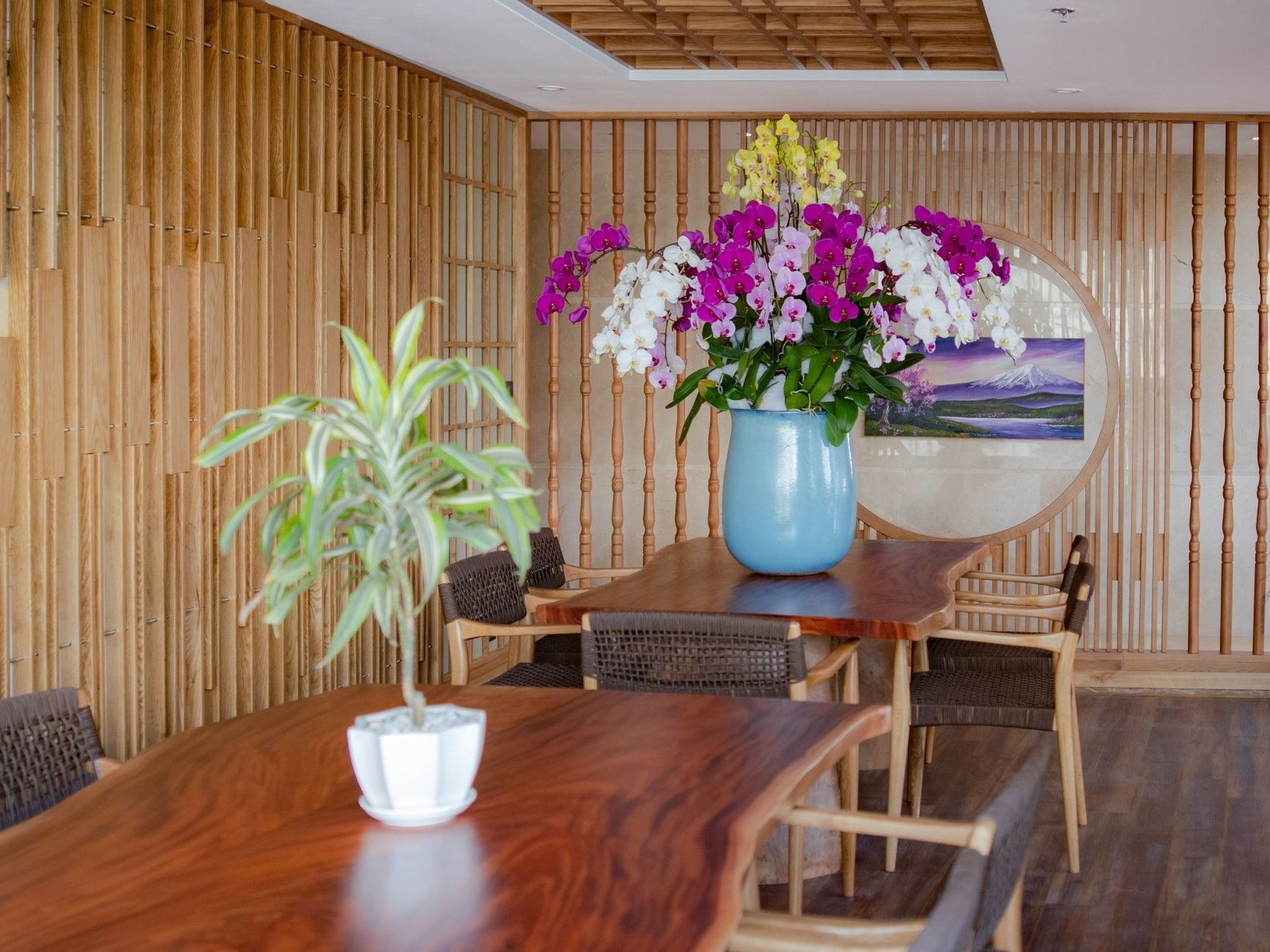 Hotel lobby with a wooden table, a vase of pink and white orchids and slatted wooden walls