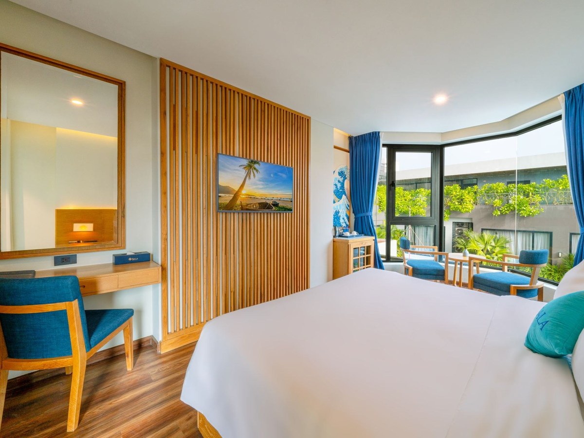 Double room with a white bed, a seascape painting above the headboard and a city-view window