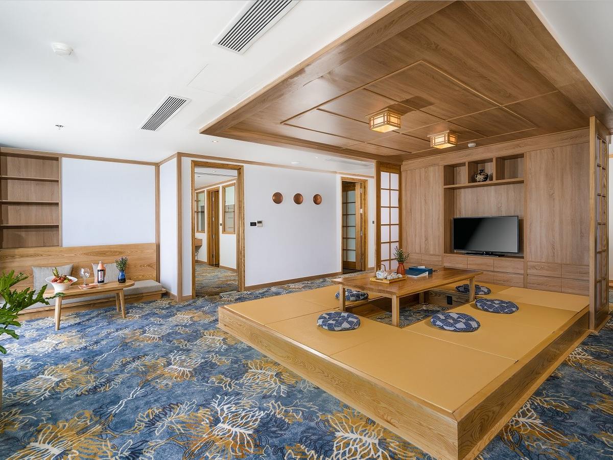 Japanese-style living room with a low table on a raised wooden platform and a kitchen along the back wall