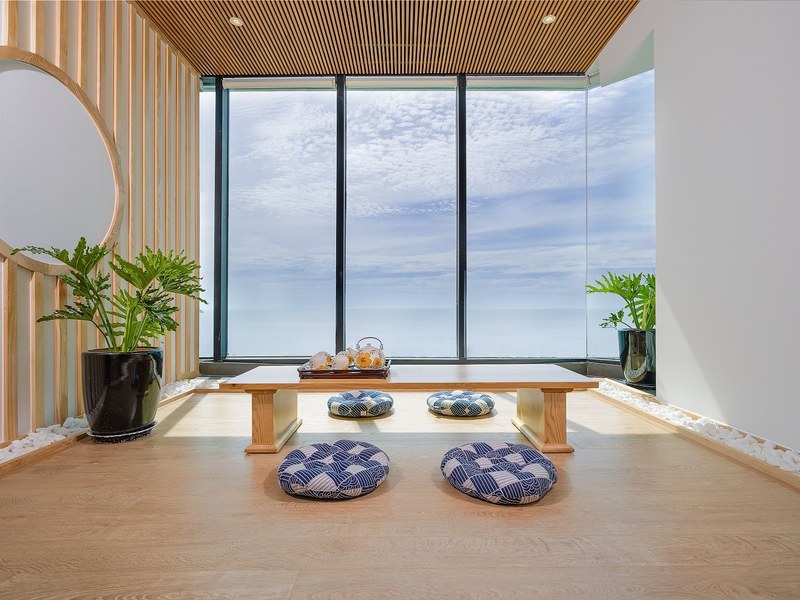 Japanese-style room with a low wooden tea table, floor cushions and a full-height window onto the sea